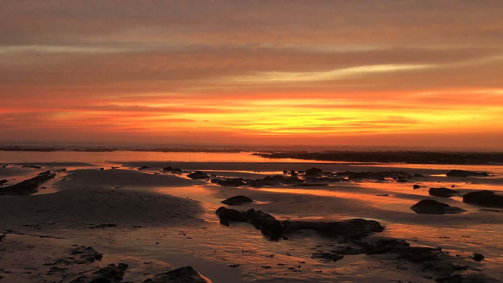 Orange sunset sky over the rocky tide pools of Playa Guiones